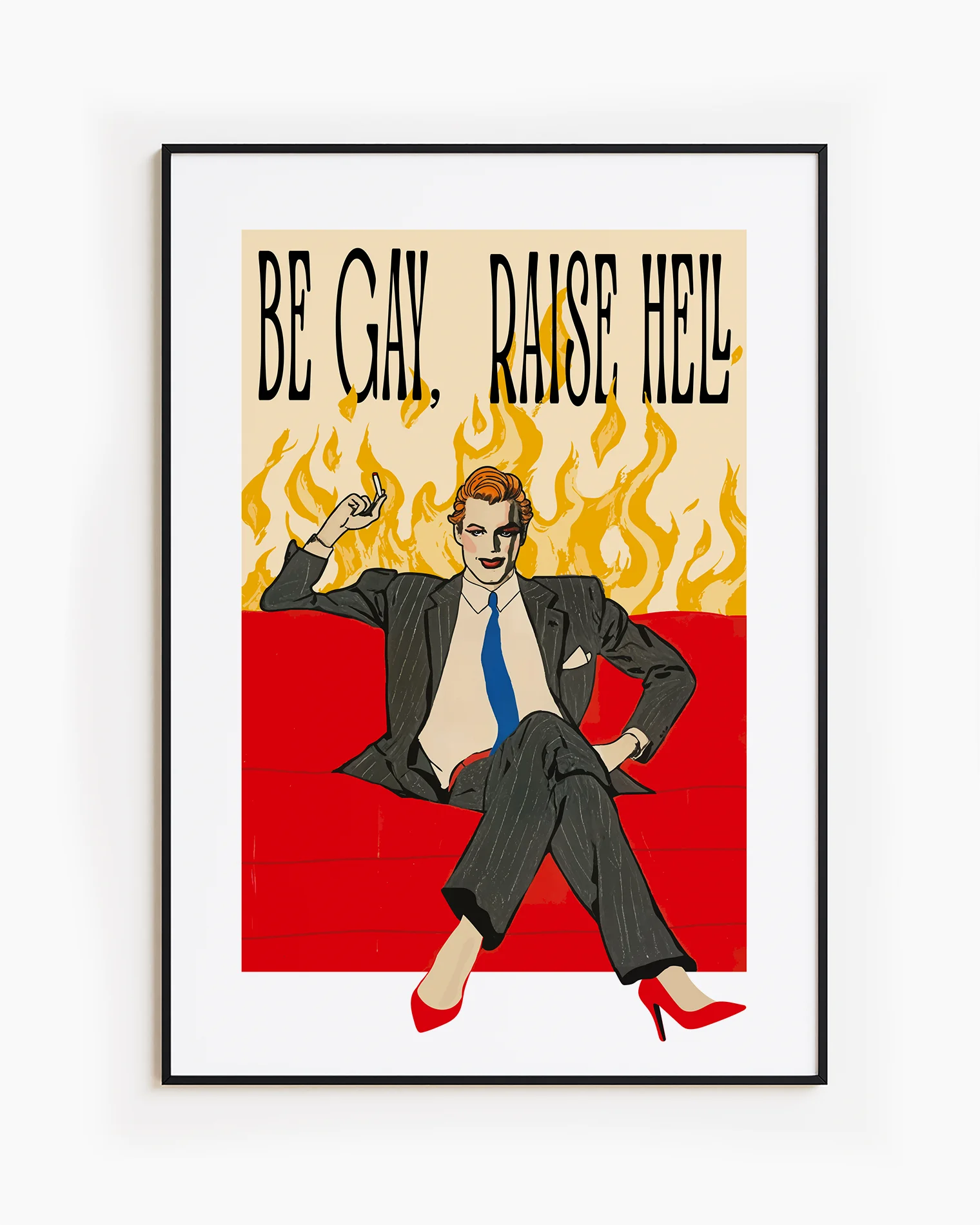 A framed poster featuring a man in make up, red high heels, sitting on a couch smoking, surrounded by massive flames, with the text "BE GAY, RAISE HELL".
