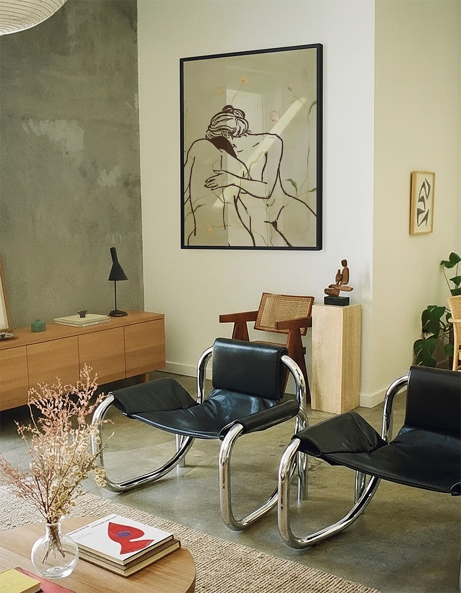 A framed print with two, naked woman holding each other in a green field.