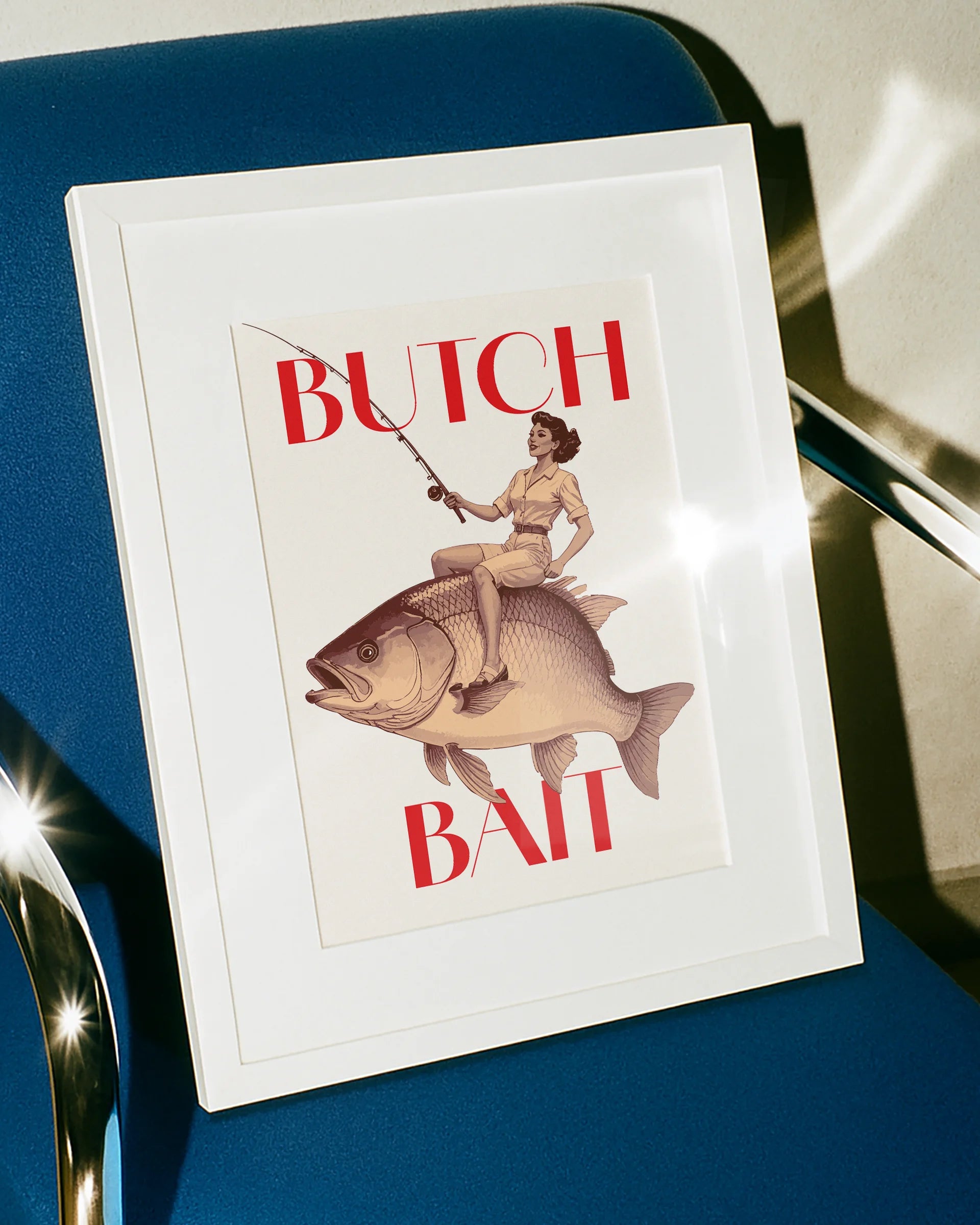 A poster depicting a lesbian woman riding a fish and holding a fishing rod, with the text ‘BUTCH BAIT'.