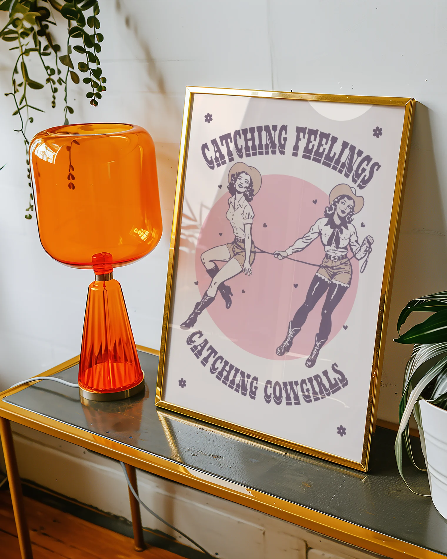 The poster features two illustrated, dreamy retro-style cowgirls capturing each other with a lasso, alongside the text: “Catching Feelings Catching Cowgirls.”