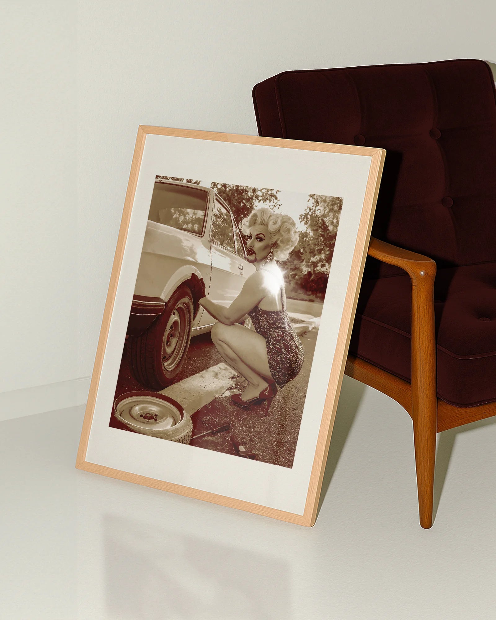 A poster featuring a fabulous drag queen in a sparkly dress, big wig, and dramatic makeup — right in the middle of a tire change.