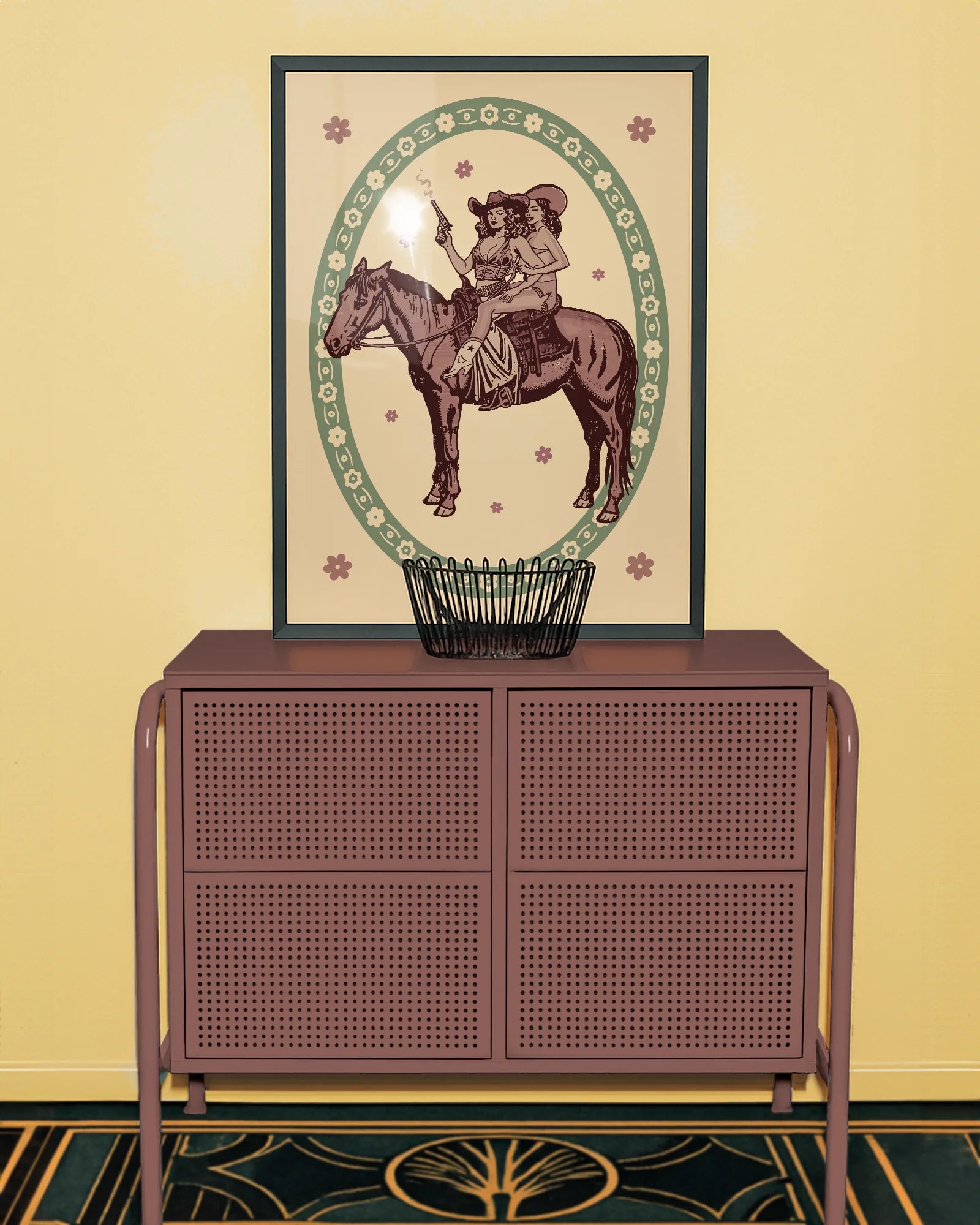A framed poster featuring two lesbian cowgirls sitting on a horse, surrounded by a retro-style floral frame.