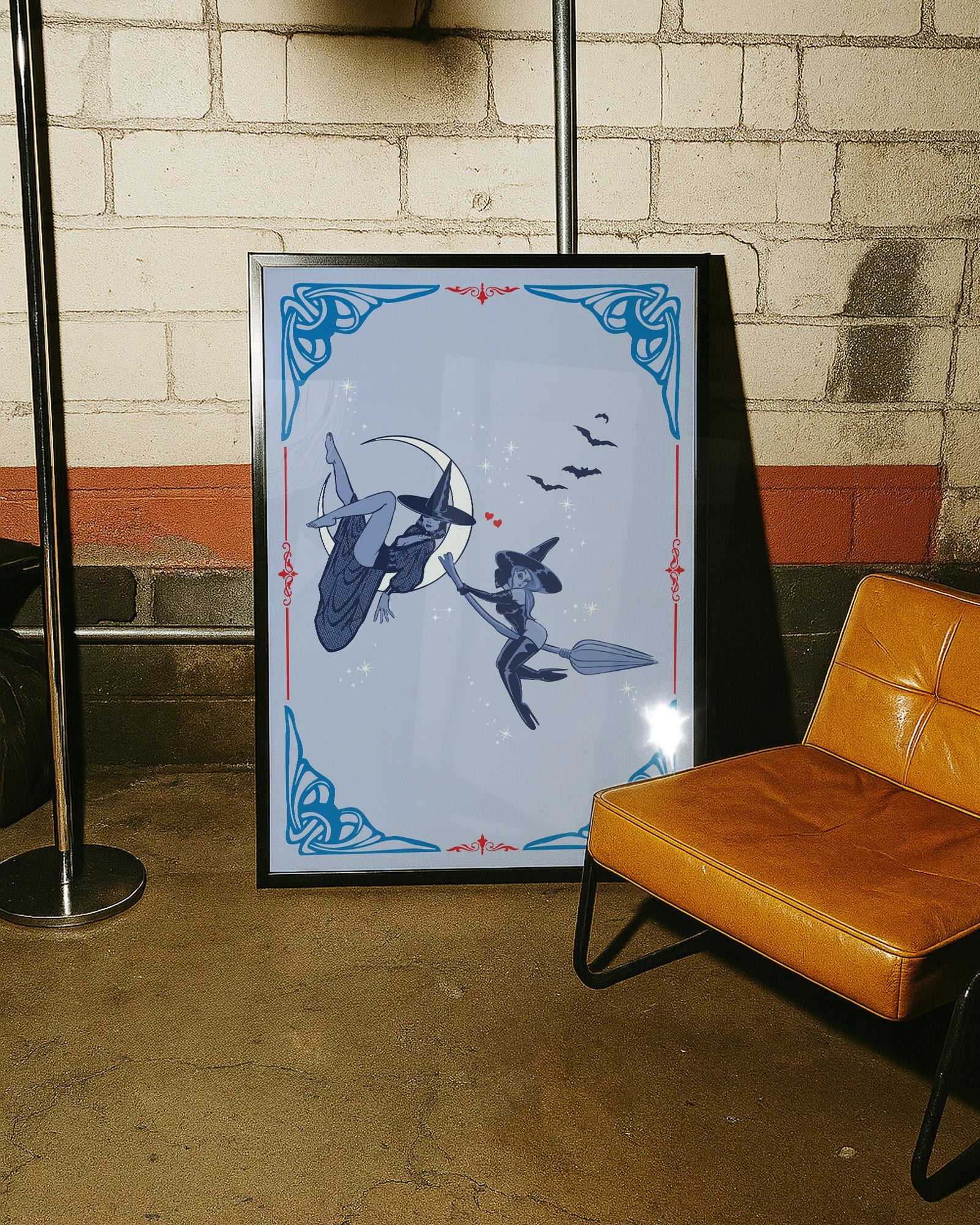 A poster featuring two lesbian witches—one flying on her broomstick while the other lies on the moon. They share a flirtatious glance, surrounded by stars and bats.