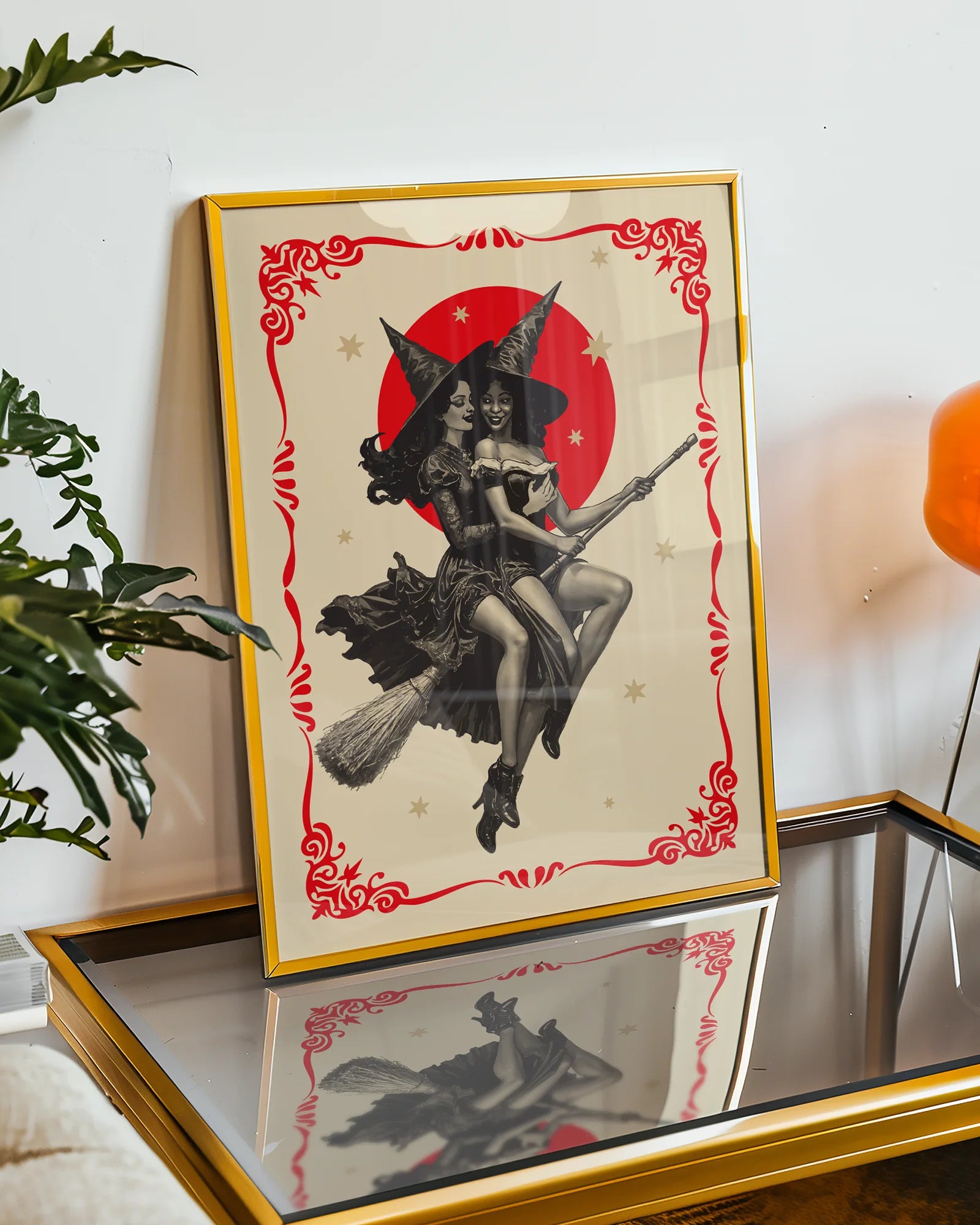 A poster featuring two lesbian witches flying on a broomstick through the night. They share a romantic gaze, surrounded by stars and a large red full moon.
