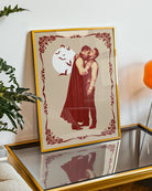 A poster featuring a male vampire kissing another man’s neck, framed by a vintage border, with a full moon and flying bats in the background.