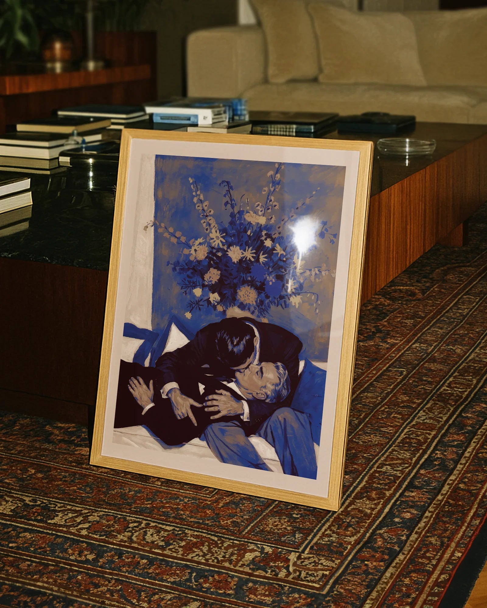 A framed poster with two, older men kissing on a couch.