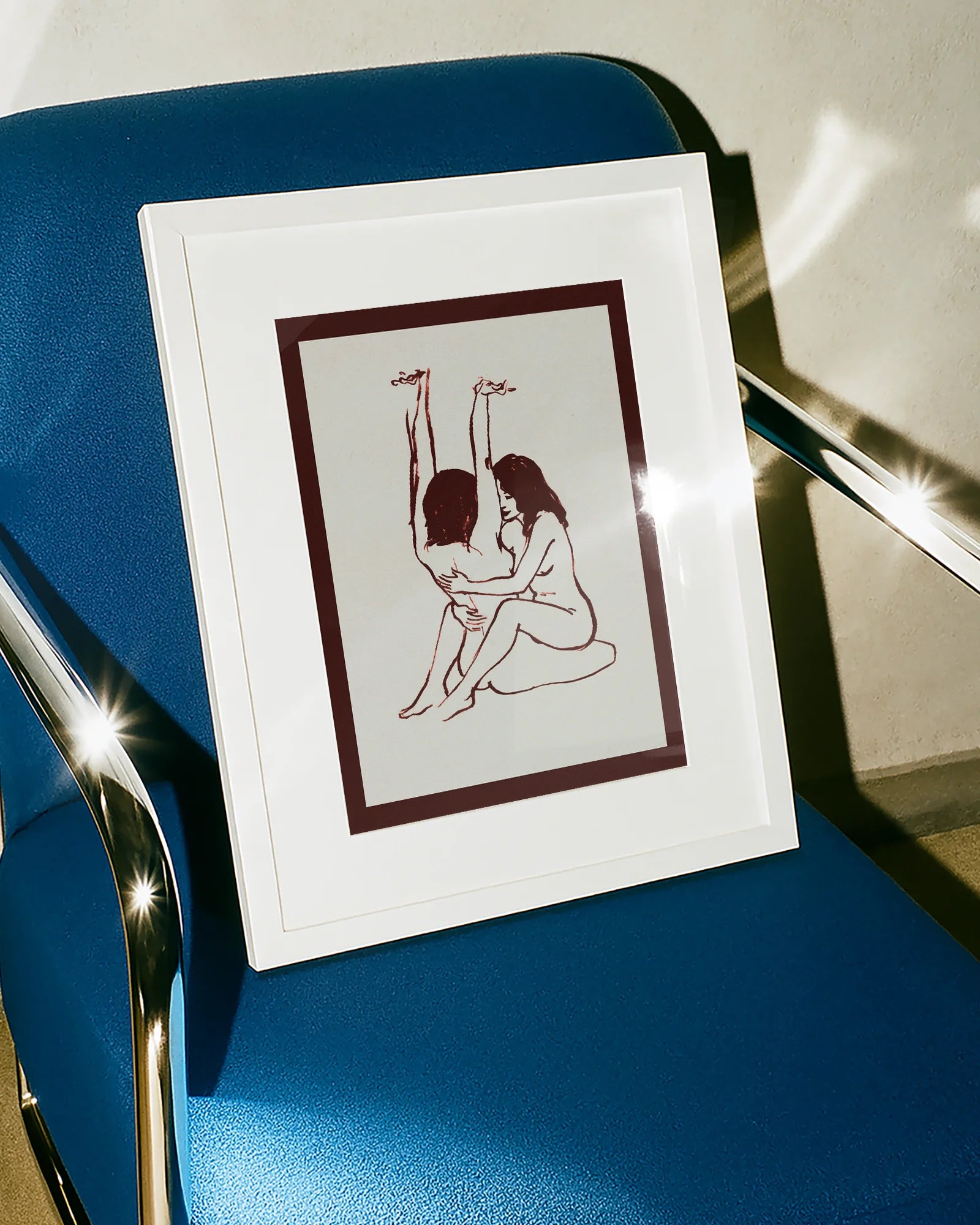 A framed print with two naked girls, hugging tight on the floor.