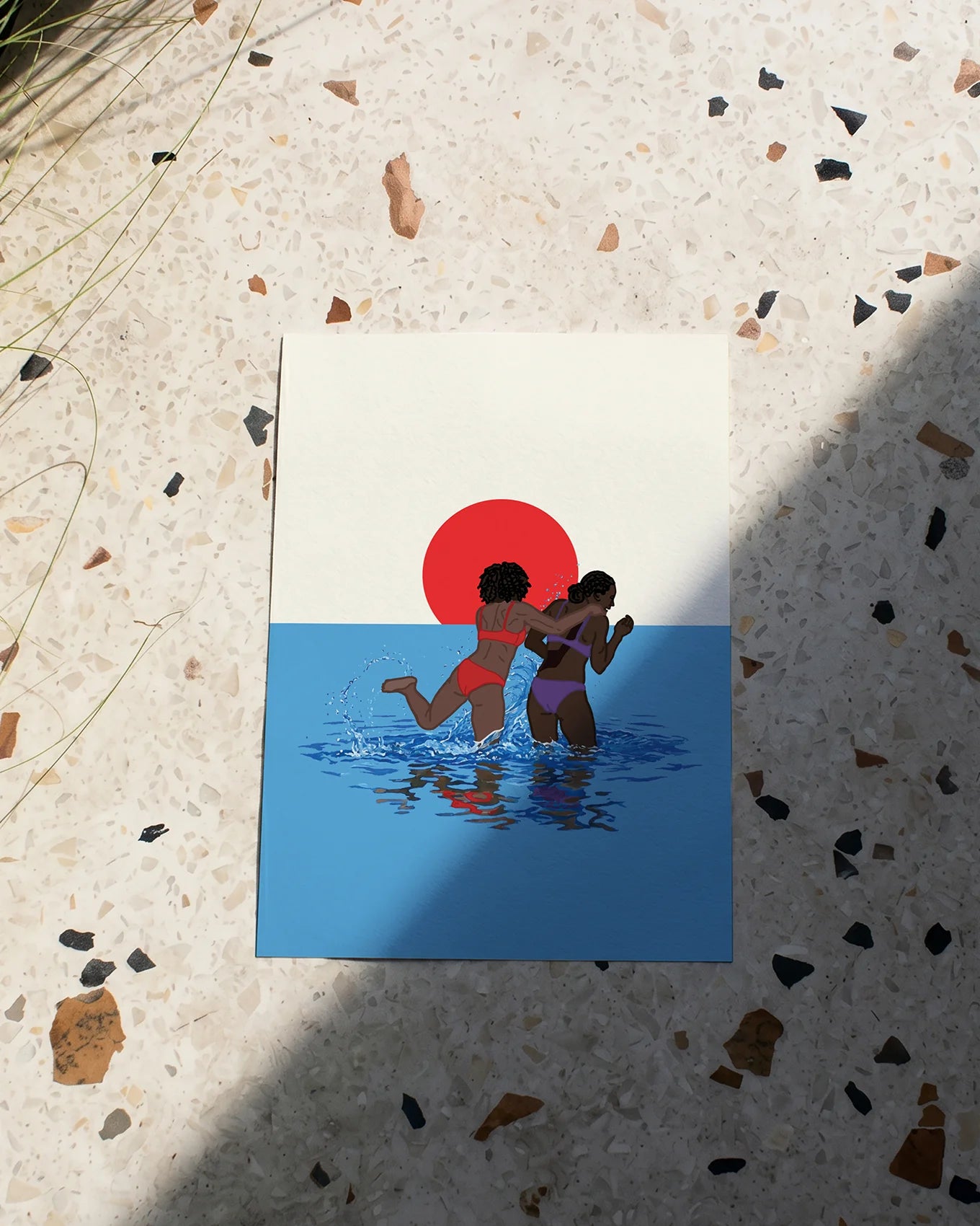 A poster with two lesbian girls playing in the ocean, in front of a sunset.