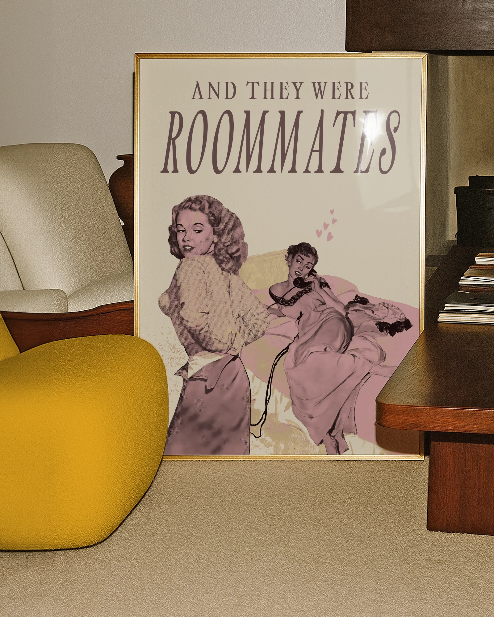 A framed poster depicting a woman lying in bed, and another woman undressing to join her — with the text “AND THEY WERE ROOMMATES.”