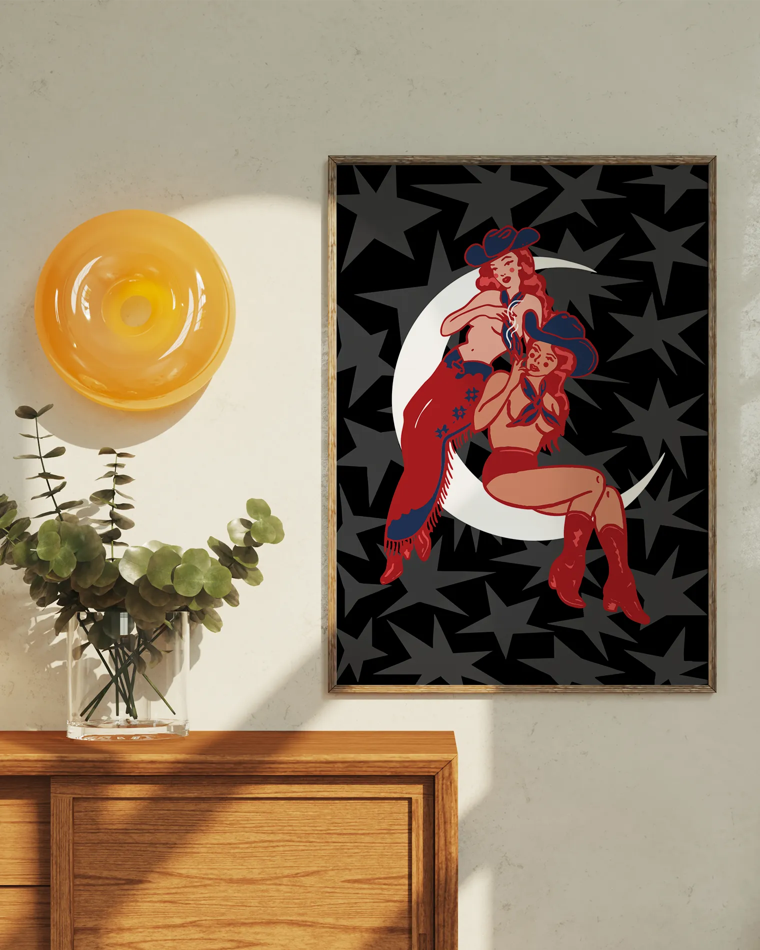 A print with two illustrated, sapphic cowgirls sitting on a moon.