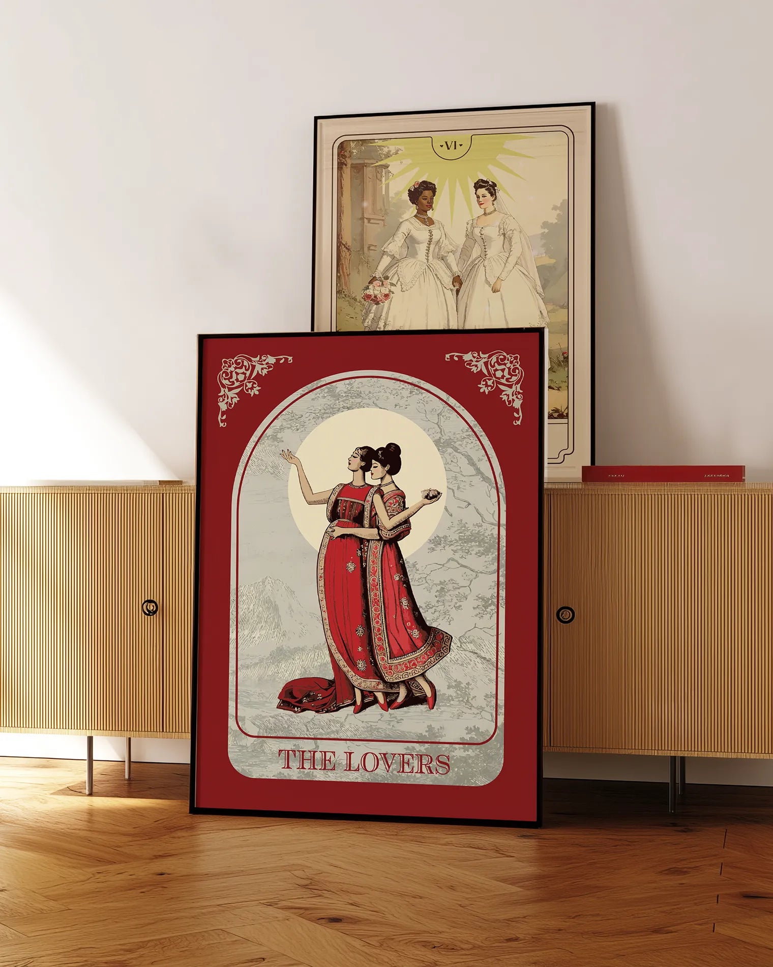 A poster with an illustrated, sapphic couple in the 1700's, posing in red dresses with the text 'The Lovers'.