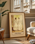 A print with an illustrated, sapphic, newlywed couple in a tarot card style with the text 'The Lovers'.