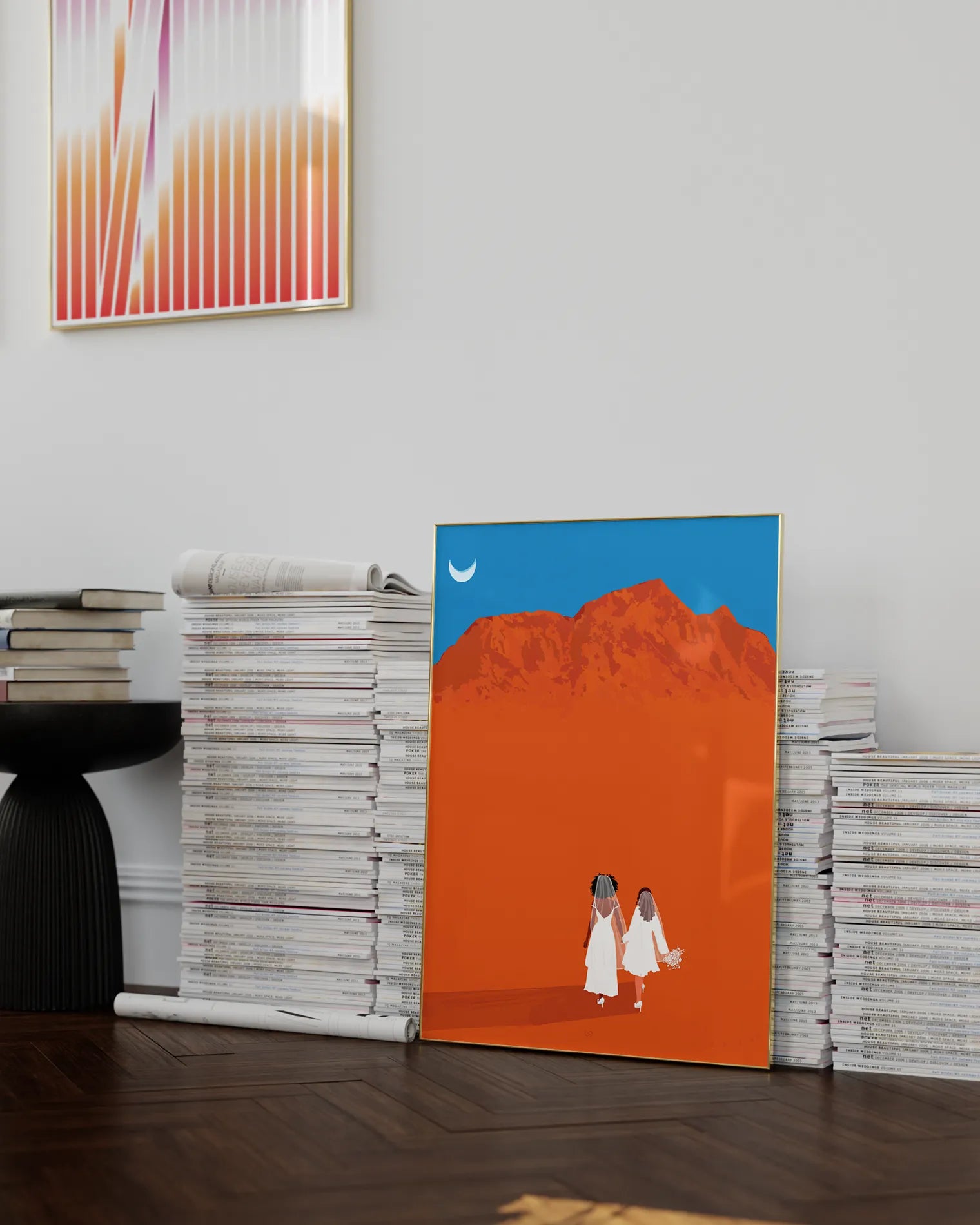 A framed print with a brides couple in white dresses walking hand in hand in a desert.