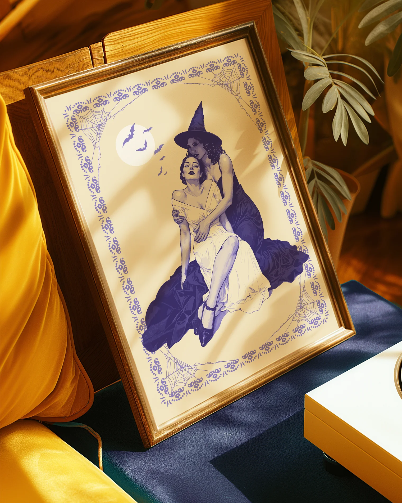 A poster with a witch tenderly holding her lover, surrounded by a spiderweb-infused frame and a large white full moon with flying bats in the background.