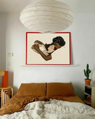 A framed, horizontal print with two lesbian women in a warm, romantic embrace.