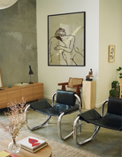 A framed print with two, naked woman holding each other in a green field.