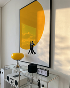 A poster of two men dancing in front of a big, yellow sun.