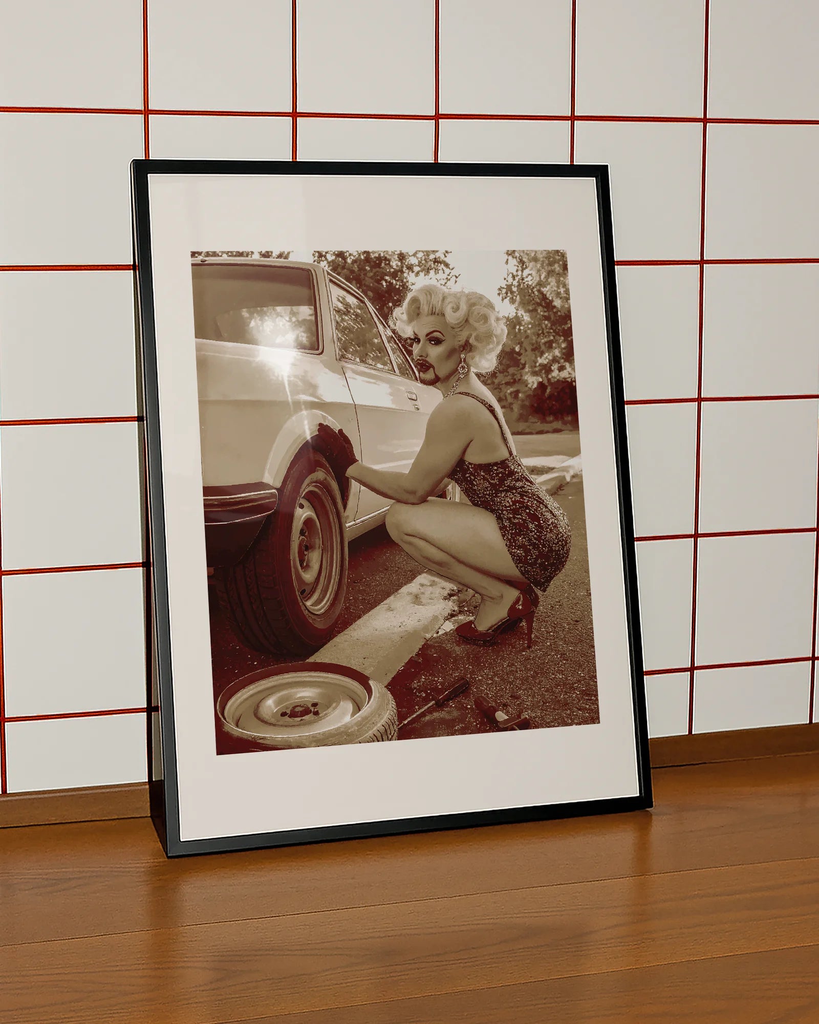 A poster featuring a fabulous drag queen in a sparkly dress, big wig, and dramatic makeup — right in the middle of a tire change.
