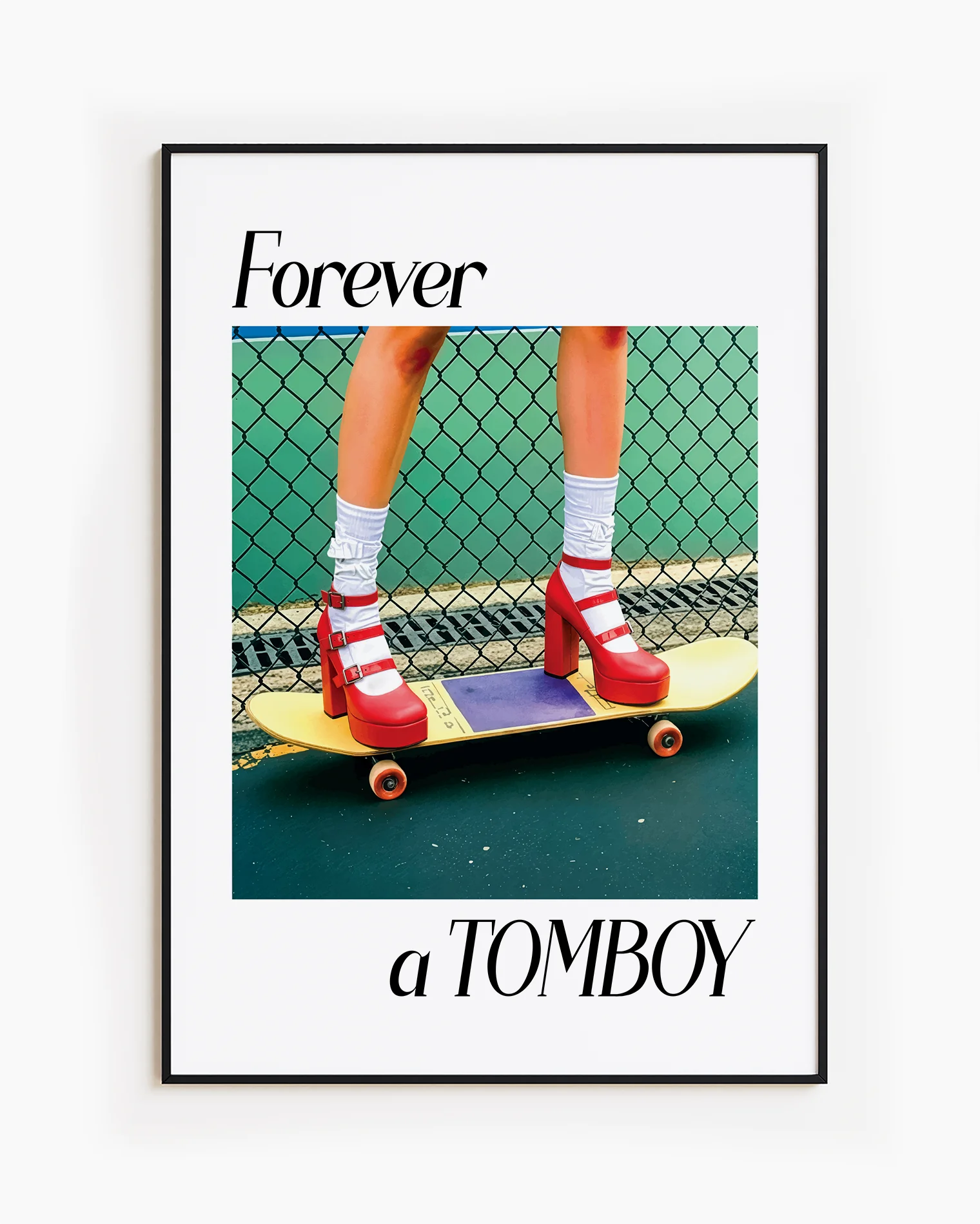 A framed print with a girl in red high heels standing on a skateboard, with the text: 'Forever a TOMBOY'.