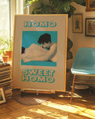 A framed poster featuring two naked men lying closely together in a soft and romantic pose, with the text: “HOMO SWEET HOMO.”