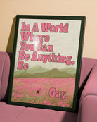 A poster of a person running through an open field of pink flowers, with a pride flag and the text: 'In a world where you can be anything, be gay'.