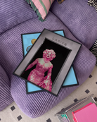 A poster with a muscular drag queen in a sparkling dress, full makeup, and wig, confidently strutting out of the ladies’ room.