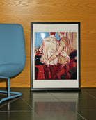 A framed poster with two gay men in a bar, ordering a drink with their hand in each other's backpockets.