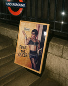 A framed poster with a black drag queen standing in front of a wall with a sign 'MEN ONLY', smiling.