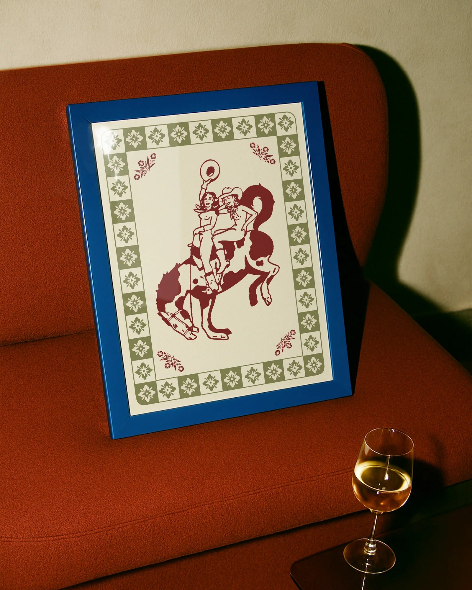 A framed poster with two, naked cowgirls riding a horse.