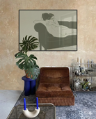 A framed, horizontal poster with two naked, lesbian ladies hugging tight on a couch.