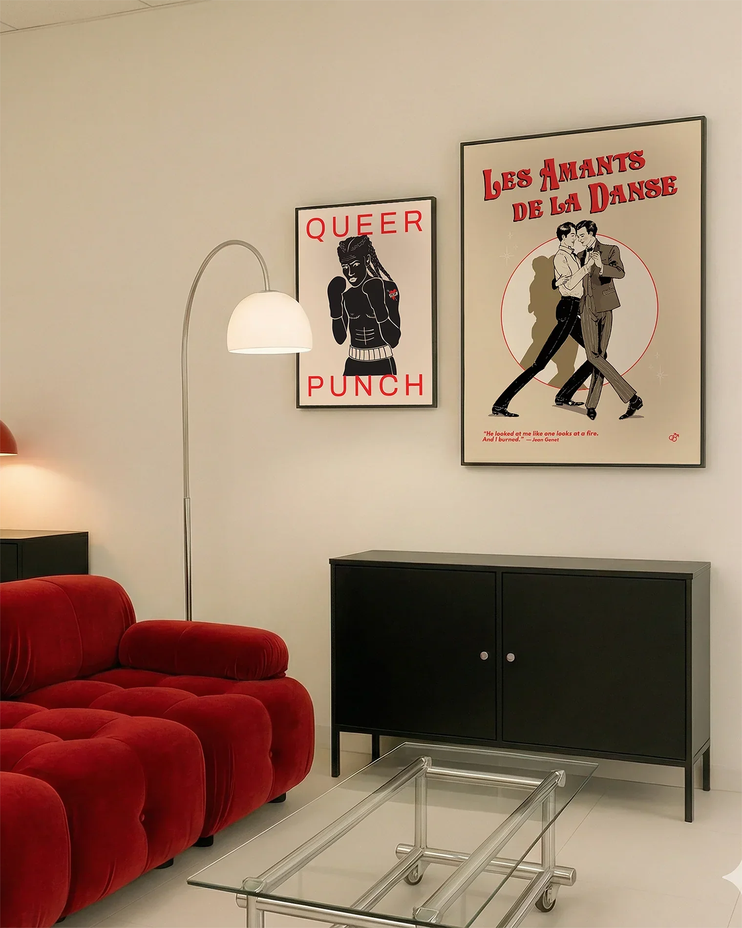 A gallery wall with several framed, queer posters in a living room.